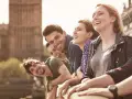 Glückliche Studenten genießen ihr Auslandssemester in England. Im Hintergrund ist das Parlament von London zu sehen.
