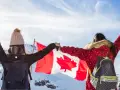 Zwei junge Frauen mit Rucksäcken und der kanadischen Flagge in den Bergen. Ein unvergesslicher Kanada Austausch!
