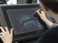 Person im Animation Studium nutzt Grafiktablett für digitale Kunst.