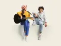 Frau mit Gitarre und Mann sitzen nebeneinander. Sie üben für ihren **spanisch austausch** und singen gemeinsam.