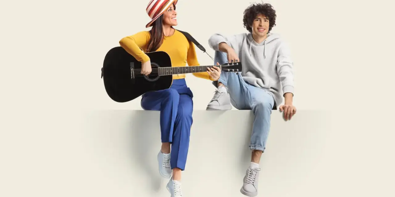Frau mit Gitarre und Mann sitzen nebeneinander. Sie üben für ihren **spanisch austausch** und singen gemeinsam.