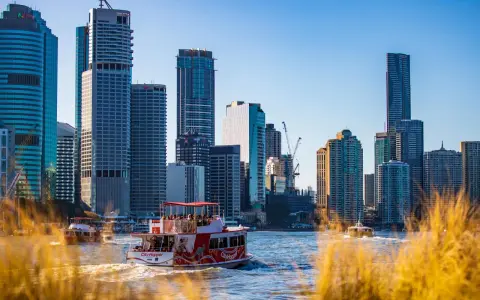 Ein Auslandssemester in Australien: Boote auf dem Fluss vor der Skyline von Brisbane mit modernen Hochhäusern.