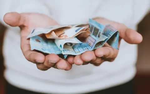 Hände halten zerknitterte Euro-Scheine. Das Geld ist für das geplante **auslandsjahr 3 monate** gedacht.