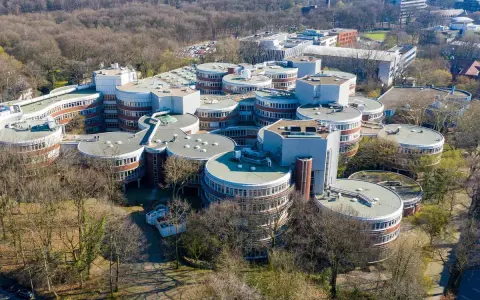 Einzigartige Architektur auf dem **Campus Duisburg**. Runde Gebäude mit vielen Fenstern gruppieren sich zu einem futuristischen Komplex inmitten von Bäumen.