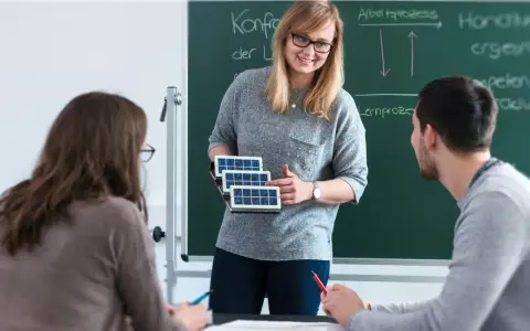 Lehrerin erklärt Schülern, wie man Berufsschullehrer wird, mit Solarzellen-Modell.