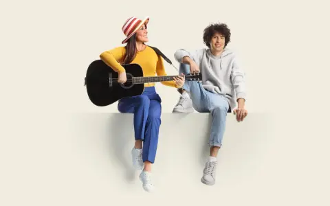 Frau mit Gitarre und Mann sitzen nebeneinander. Sie üben für ihren **spanisch austausch** und singen gemeinsam.