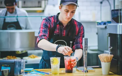 Ein junger Mann, der als Werkstudent 20 Stunden pro Woche arbeitet, mixt Getränke in einem Streetfood-Laden.