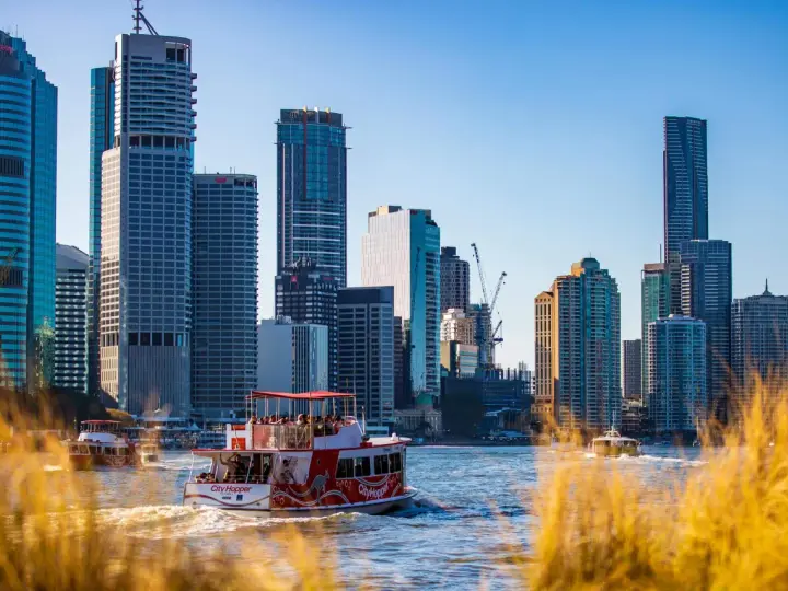 Ein Auslandssemester in Australien: Boote auf dem Fluss vor der Skyline von Brisbane mit modernen Hochhäusern.