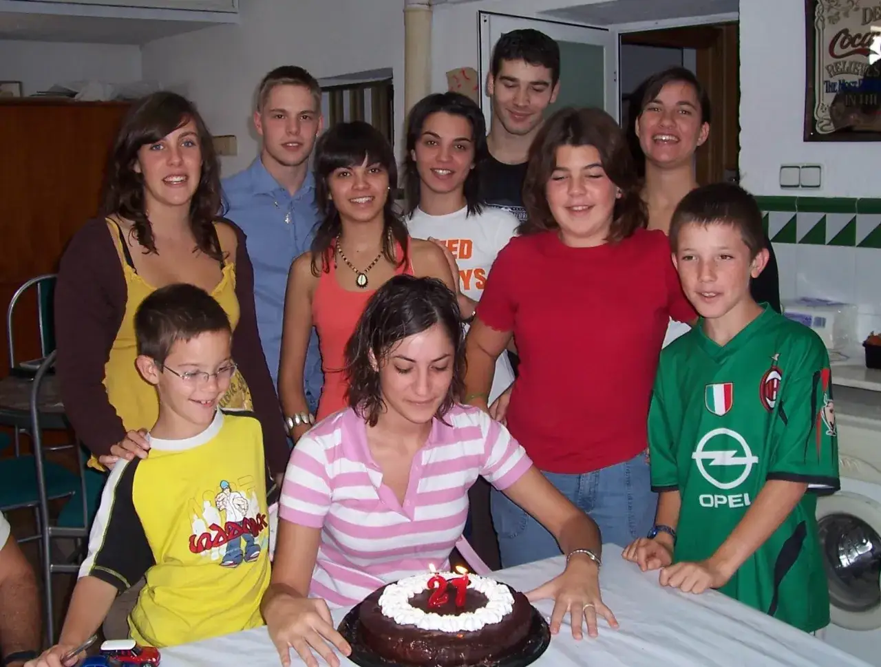 Gruppe feiert Geburtstag mit Kuchen. Ein Junge im Fußballtrikot, ein Mädchen mit Kerzen auf dem Kuchen. Ein schöner Moment des spanisch austausch.