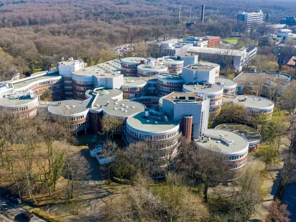 Einzigartige Architektur auf dem **Campus Duisburg**. Runde Gebäude mit vielen Fenstern gruppieren sich zu einem futuristischen Komplex inmitten von Bäumen.